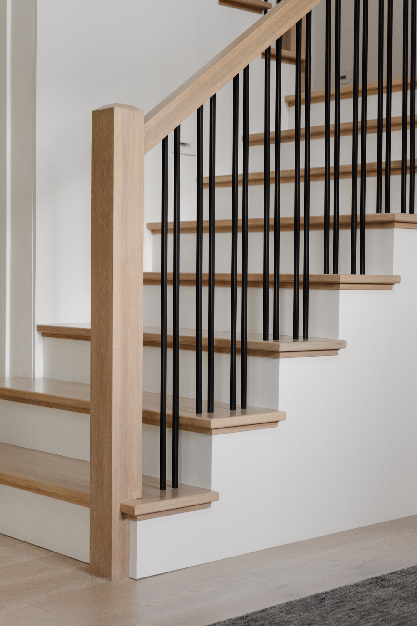 Modern floating stairs white white oak and iron balusters. Interior Design by LC Interiors, best interior designer in Naperville, Illinois.
