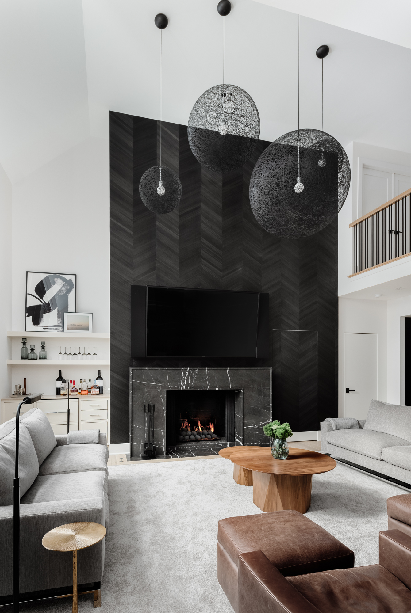 Modern living room with black marble fireplace and chevron wallpaper, black windows, white walls, dry bar. Interior Design by LC Interiors, best interior designer in Naperville, Illinois.