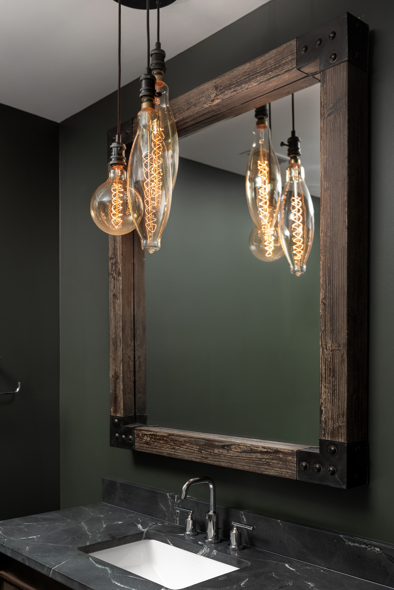 Masculine and dark basement powder room with wood mirror and vanity and gray stone and walls.